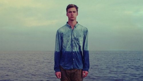 Junge am Meer; das Wasser steht ihm scheinbar bis zum Bauchnabel