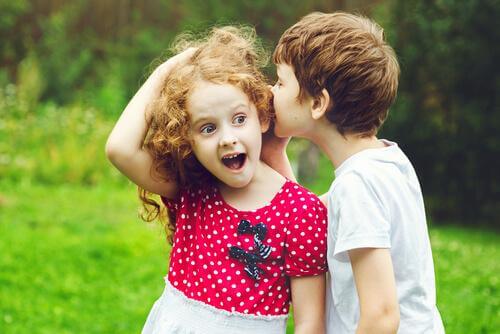 Ein Junge flüstert einem Mädchen etwas ins Ohr