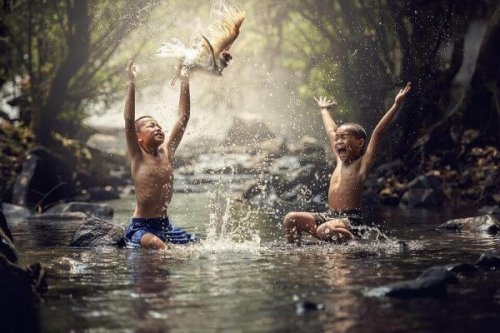 Zwei asiatische Jungen spielen in einem Fluss. 