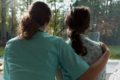 Eine Krankenschwester hat ihren Arm um eine Patientin gelegt.