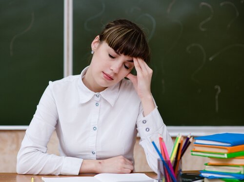 Eine Lehrerin hat Kopfschmerzen vor lauter Stress.