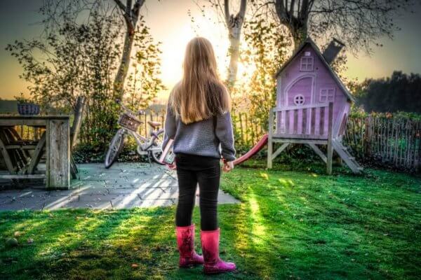 Ein Mädchen steht allein in einem Garten.