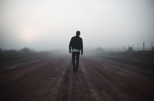 Ein Mann auf einem Weg im Nebel.