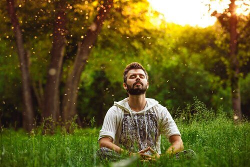 Ein Mann sitzt in einem Feld und meditiert. 