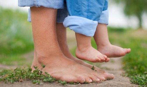 Die Füße einer Mutter und ihres kleinen Kindes, das sie hochhält.