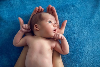 Ein Neugeborenes liegt auf einer blauen Decke.