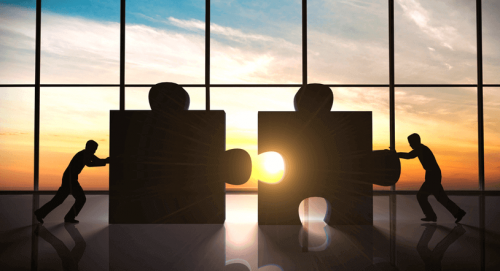 Personen schieben Puzzleteile zusammen.