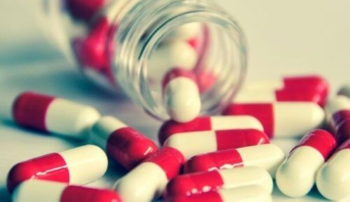 Rot-weiße Kapseln fallen aus einem Glas.