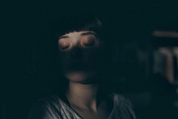 Eine junge Frau schläft in der Dunkelheit. 