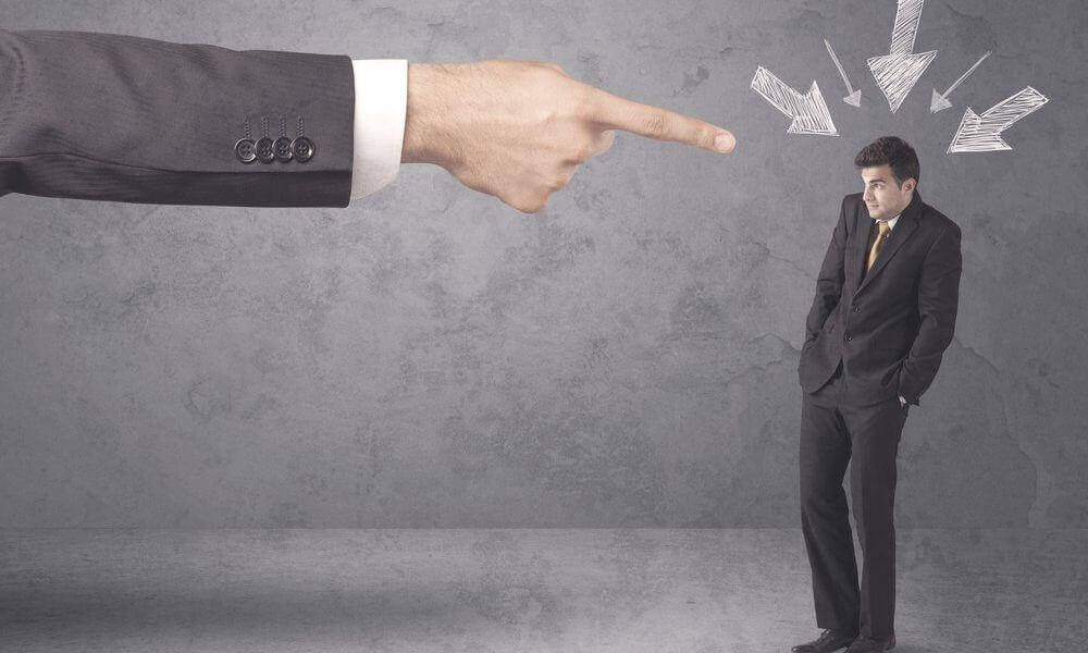 Finger zeigt verurteilend auf einen eingeschüchterten Mann