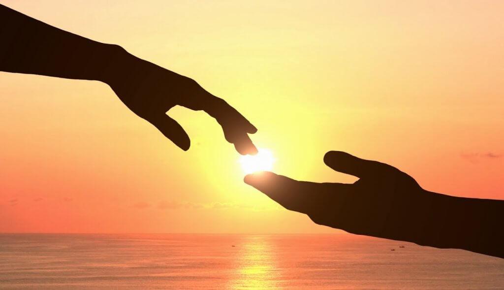 Hände berühren sich bei Sonnenaufgang