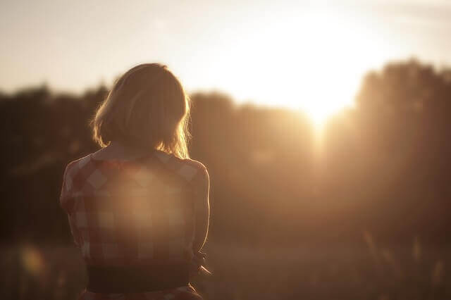 Traurige Frau, die sich den Sonnenuntergang ansieht