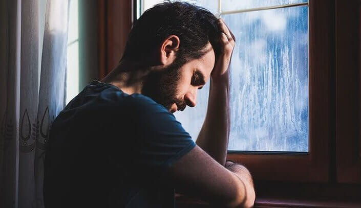 Trauriger Mann, der vor dem Fenster steht