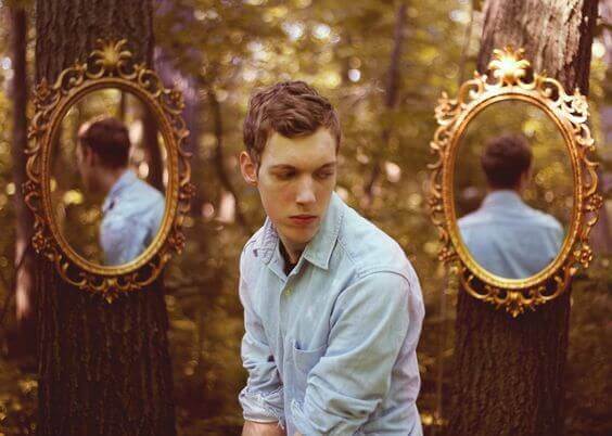 Mann sitzt zwischen zwei Spiegeln im Wald