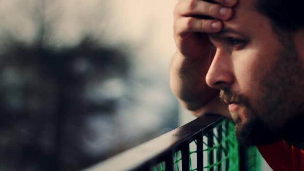 Erschöpfter Mann stützt seinen Kopf auf ein Geländer