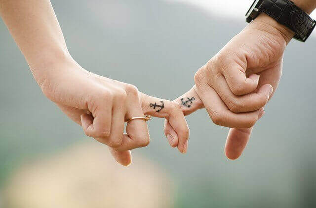 Händchenhalten mit Fingern mit Anker-Partner-Tattoo