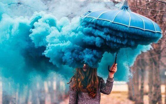 Frau mit blauem Regenschirm und blauem Rauch