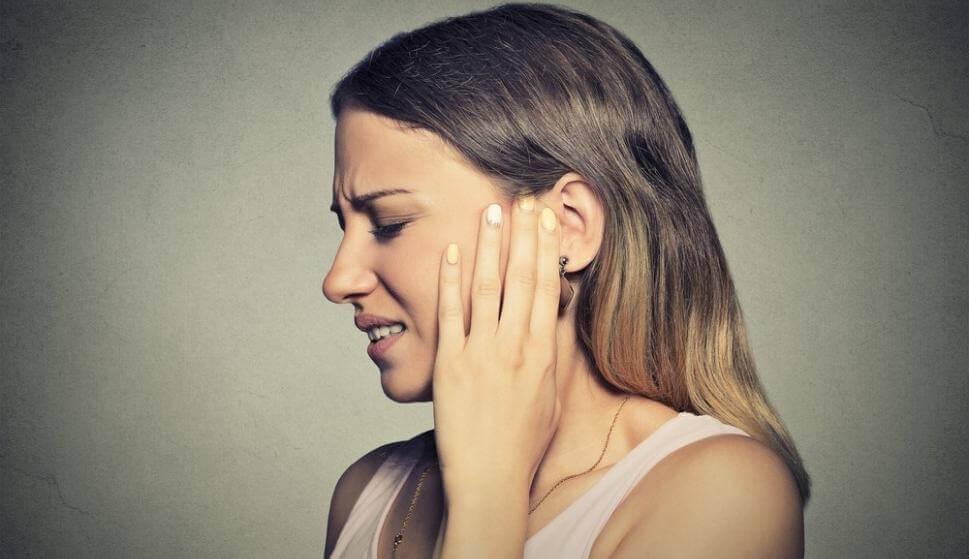 Eine Frau, die unter Misophonie leidet, fasst sich ans Ohr.
