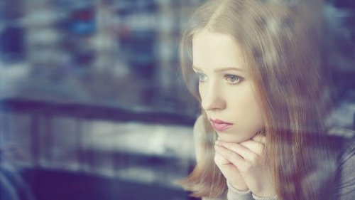 Frau schaut traurig aus dem Fenster