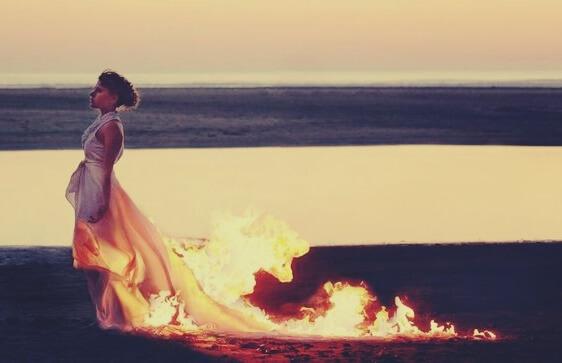 Frau mit weißem Kleid steht in Flammen