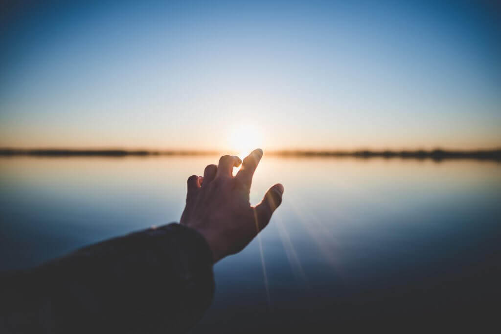 Hand, die die Sonne berührt