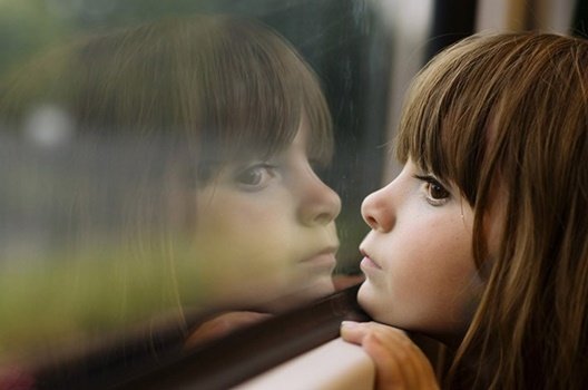 Ein Mädchen schaut aus einem Fenster. 