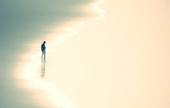 Ein Mann steht allein am Strand.