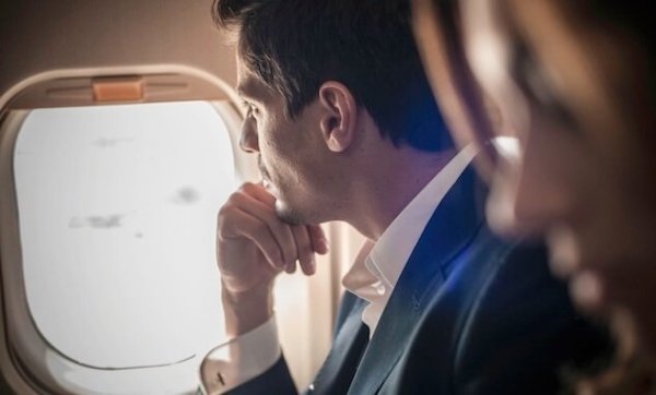 Ein Mann starrt aus einem Flugzeugfenster. 