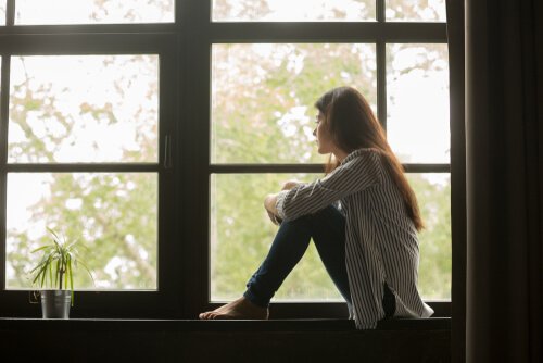 Traurige Frau sitzt beim Fenster