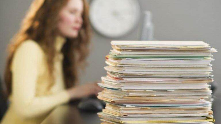 Frau mit einem riesigen Stapel Arbeit