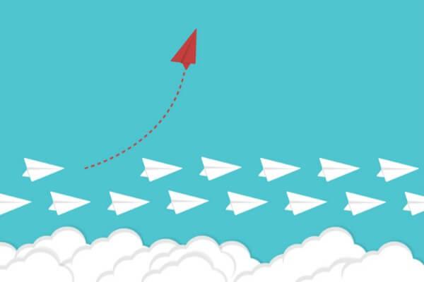 Viele weiße Papierflieger mit einem roten, nach oben ausweichenden Papierflieger