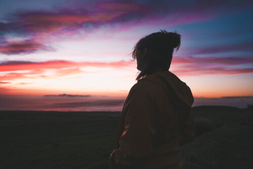 Frau sieht sich allein im Morgengrauen den Himmel an