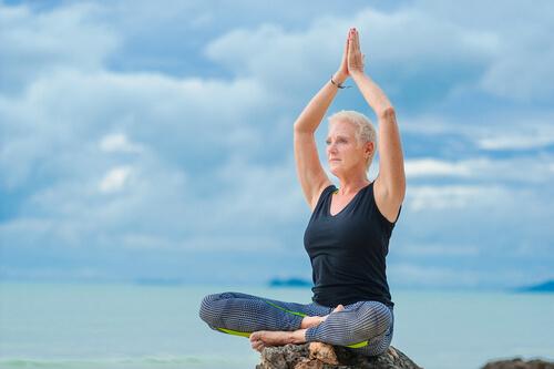 Frau in fortgeschrittenem Alter praktiziert Yoga am Meer