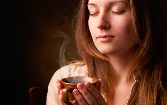 Frau mit geschlossenen Augen genießt den Geruch von Kaffee