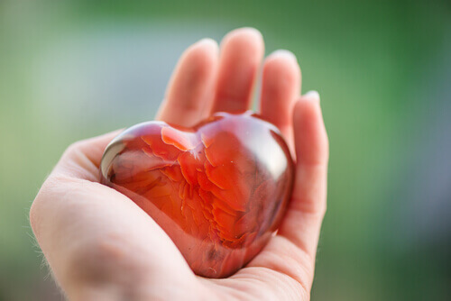 Rotes Herz aus Glas liegt in einer Hand