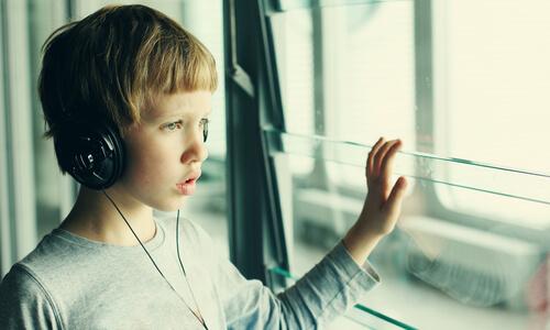 Autistischer Junge hört Musik und schaut aus dem Fenster