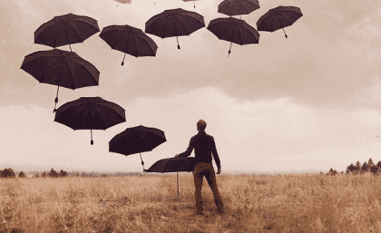 Mann mit Regenschirmen auf einem Feld