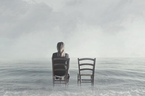 Frau sitzt auf einem Stuhl neben einem leeren Stuhl im Wasser