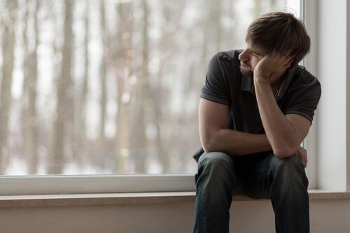 Mann sitzt verzweifelt am Fenster