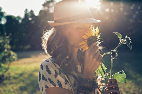Frau riecht an einer Sonnenblume