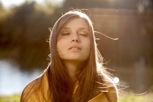 Ein Mädchen genießt die Sonnenstrahlen in seinem Gesicht.