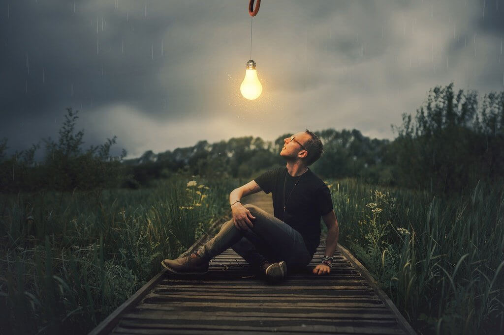 Mann, der auf eine Glühbirne blickt, die über ihm hängt