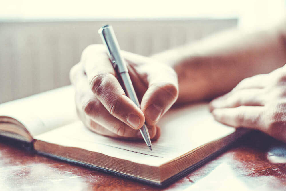 Eine Hand hält einen Stift und scheint Notizen zu machen. 