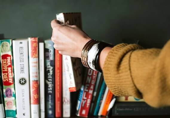 Frau greift in ein Bücherregal