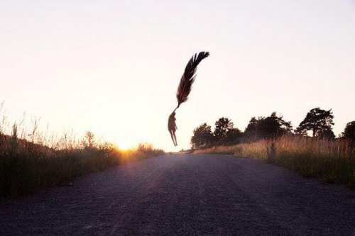 Figur hält sich an einer riesigen Feder fest