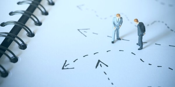 Zwei Spielzeugfiguren stehen auf einem Notizbuch und scheinen die Notizen zu betrachten.