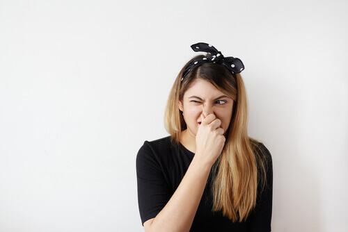 Eine junge Frau hält sich die Nase zu.