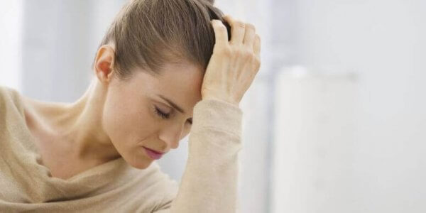 Eine nachdenkliche junge Frau hat ihren Kopf auf ihre Hand gestützt.