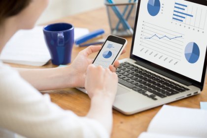 Eine Frau sitzt vor ihrem Laptop und sieht sich Statistiken an.