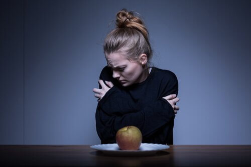 Frau mit unangemessenem Körperbild vor Apfel